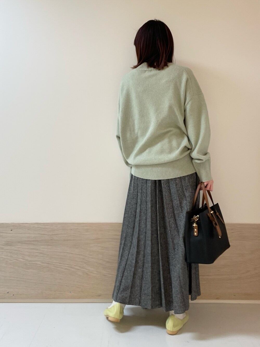 グリーン系のニット/セーター、イエロー系のバレエシューズ、ブルー系のスカートを着用したレディースの冬コーディネートの6枚目の写真