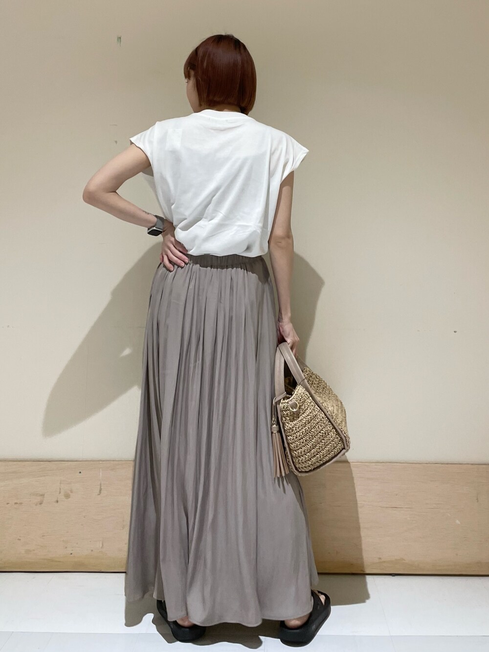 グレー系のスカート、ホワイト系のTシャツ/カットソー、ベージュ系のかごバッグを着用したレディースの春コーディネートの7枚目の写真
