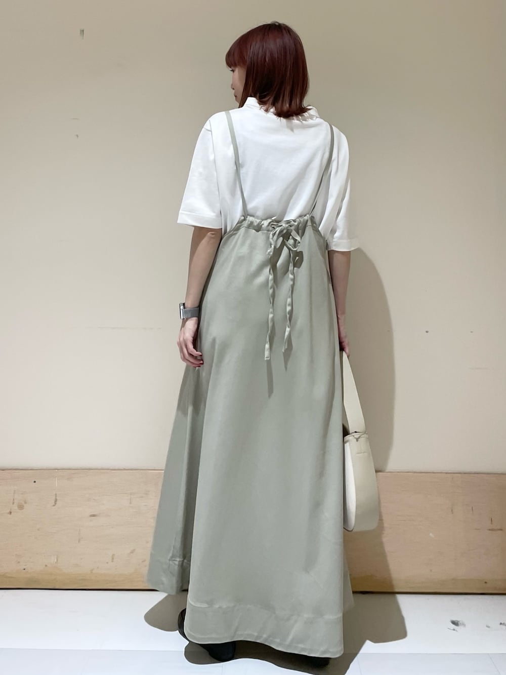 ベージュ系のハンドバッグ、ブラック系のスリッポン、ホワイト系のTシャツ/カットソーを着用したレディースの春コーディネートの5枚目の写真