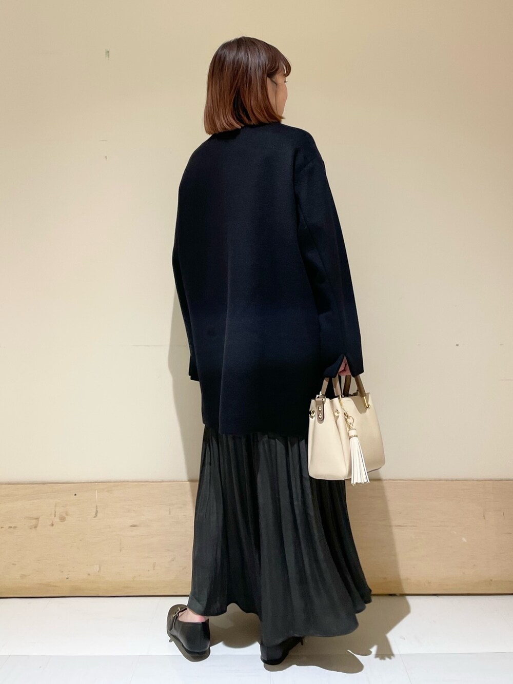 グリーン系のスカート、グレー系のニット/セーター、ブラック系のその他アウターを着用したレディースの冬コーディネートの7枚目の写真