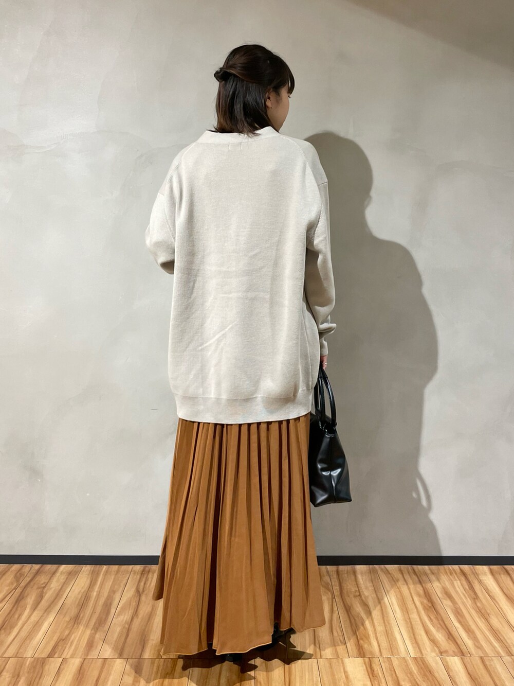 ブラック系のハンドバッグ、イエロー系のスカート、ホワイト系のTシャツ/カットソーを着用したレディースの秋コーディネートの4枚目の写真