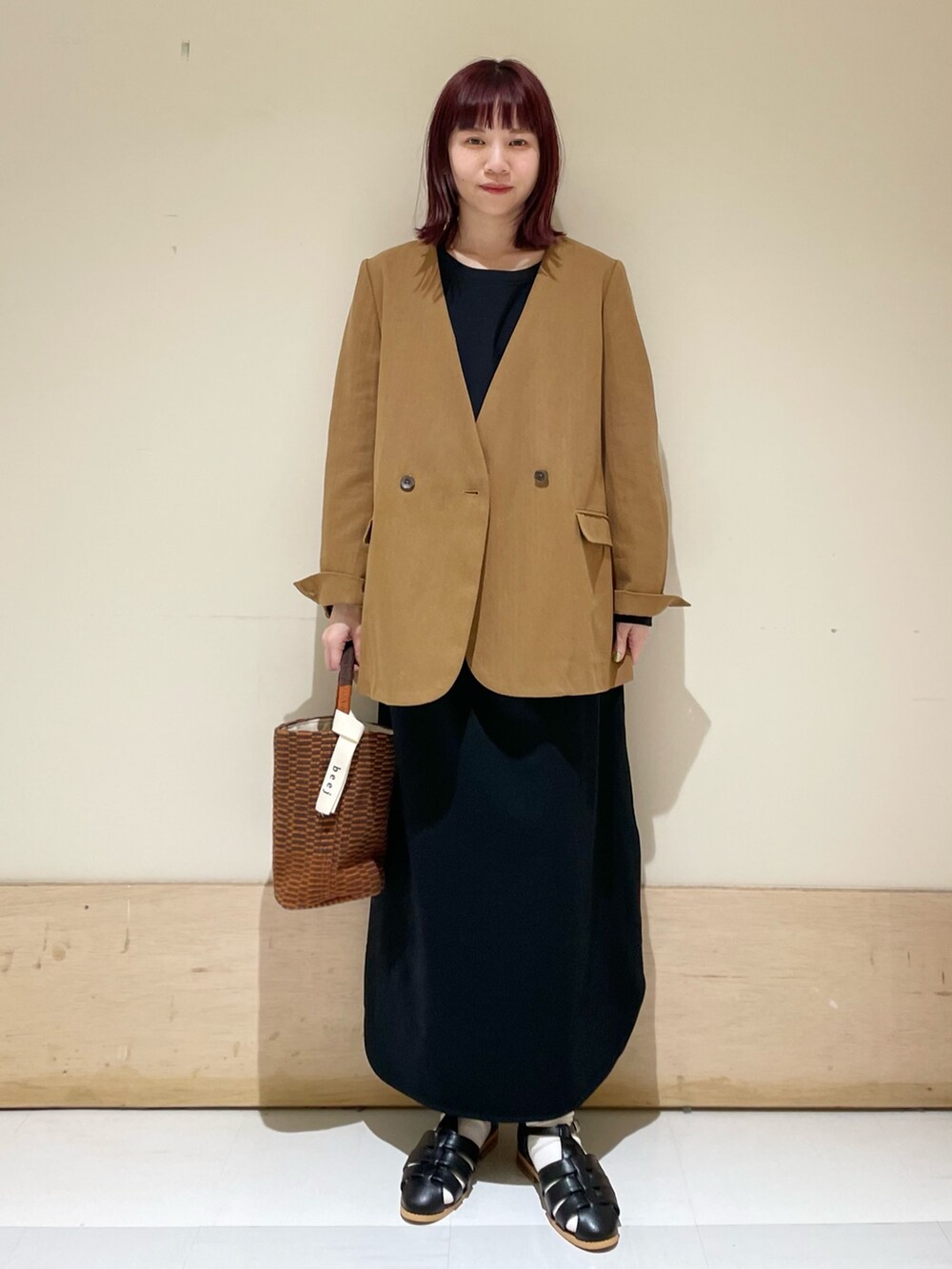 ブラック系のワンピース、ベージュ系のノーカラージャケット、ブラック系のサンダルを着用したレディースの春コーディネートの2枚目の写真