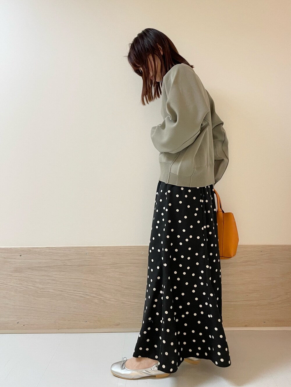 ブラック系のスカート、シルバー系のバレエシューズ、グリーン系のニット/セーターを着用したレディースの春コーディネートの4枚目の写真