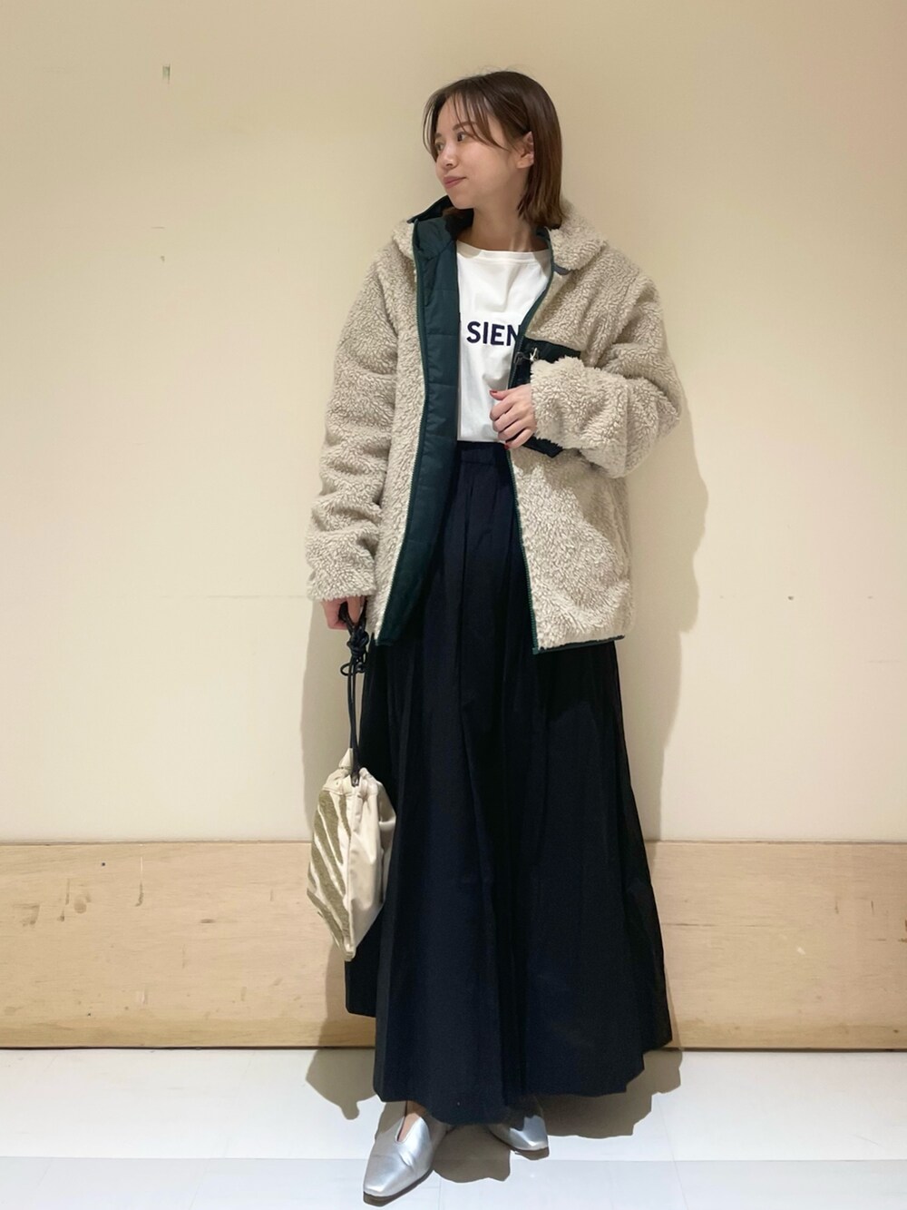 シルバー系のパンプス、ブルー系のTシャツ/カットソー、ベージュ系のハンドバッグを着用したレディースの秋コーディネートの4枚目の写真