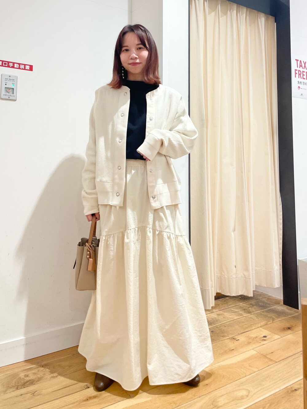 ホワイト系のカーディガン/ボレロ、ブラック系のTシャツ/カットソー、ホワイト系のスカートを着用したレディースの春コーディネートの2枚目の写真