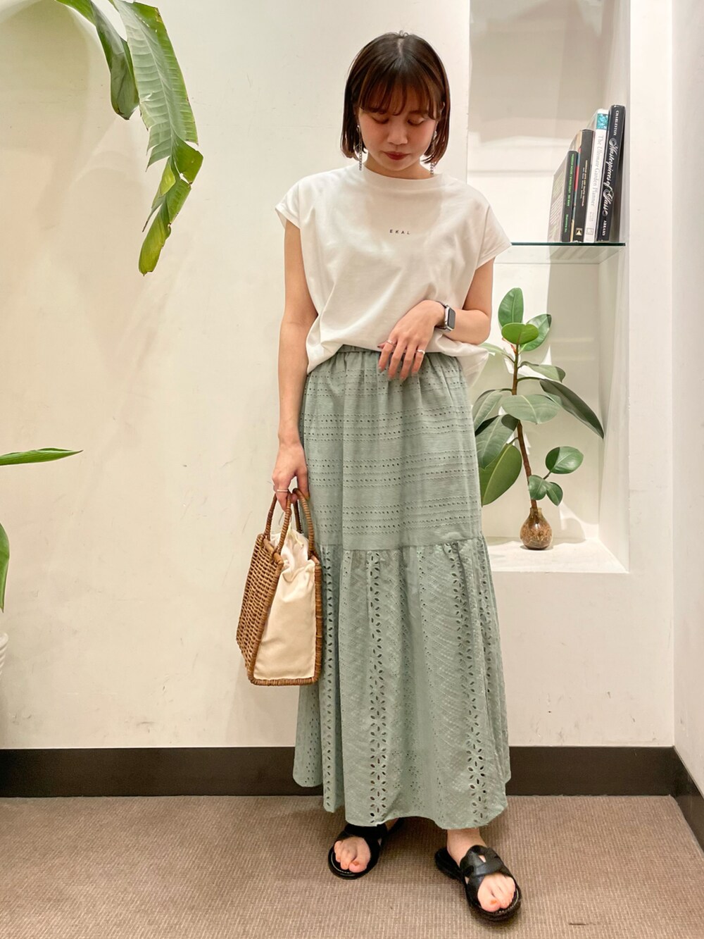 ホワイト系のハンドバッグ、ホワイト系のTシャツ/カットソー、グリーン系のスカートを着用したレディースの夏コーディネートの2枚目の写真