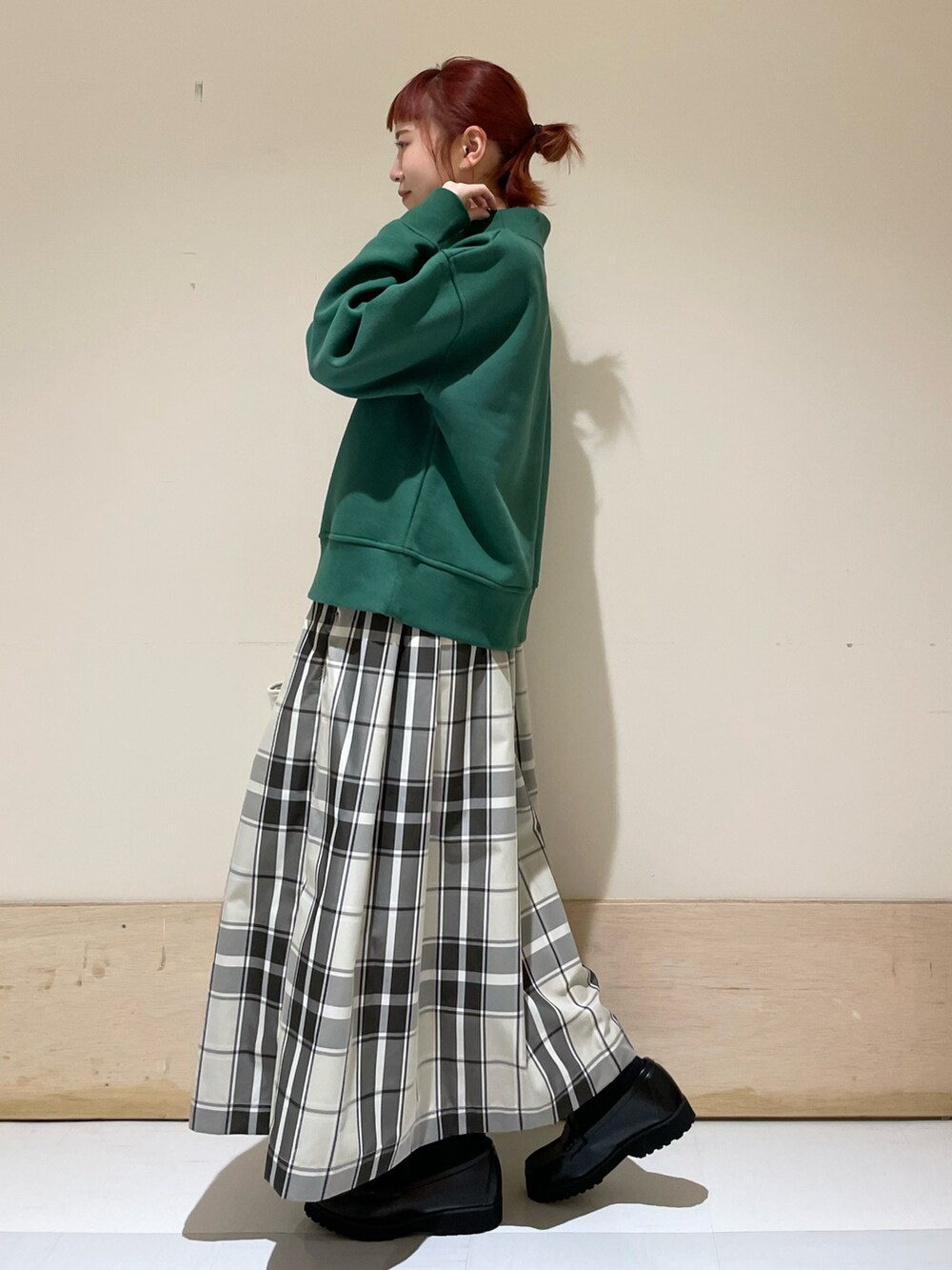 グリーン系のスウェット、ベージュ系のスカート、ブラック系のローファーを着用したレディースの冬コーディネートの4枚目の写真