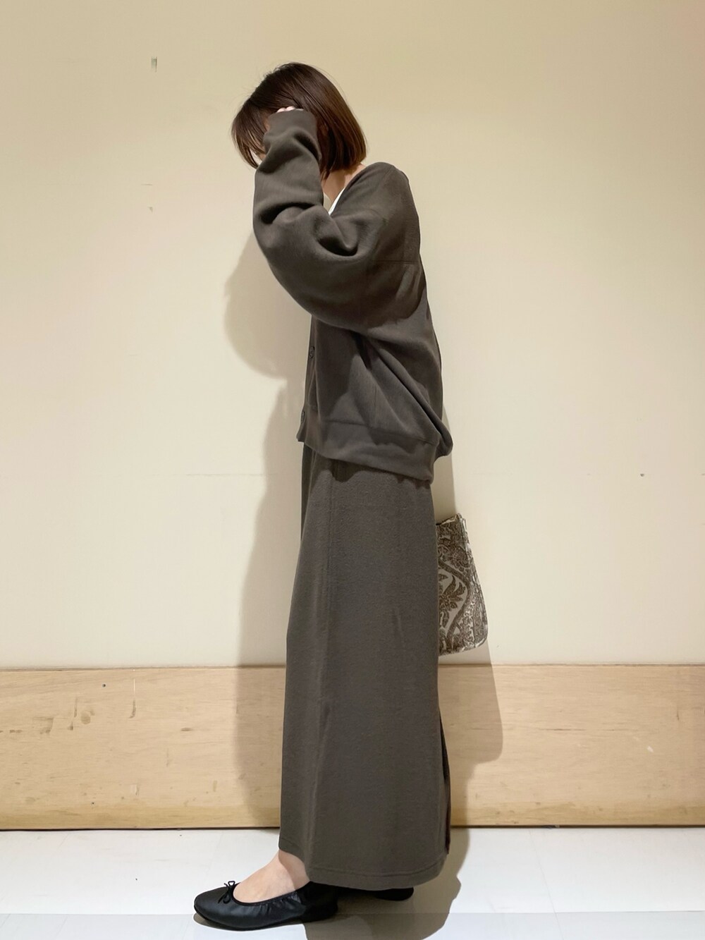 ベージュ系のトートバッグ、ホワイト系のタンクトップ、グレー系のカーディガン/ボレロを着用したレディースの秋コーディネートの5枚目の写真