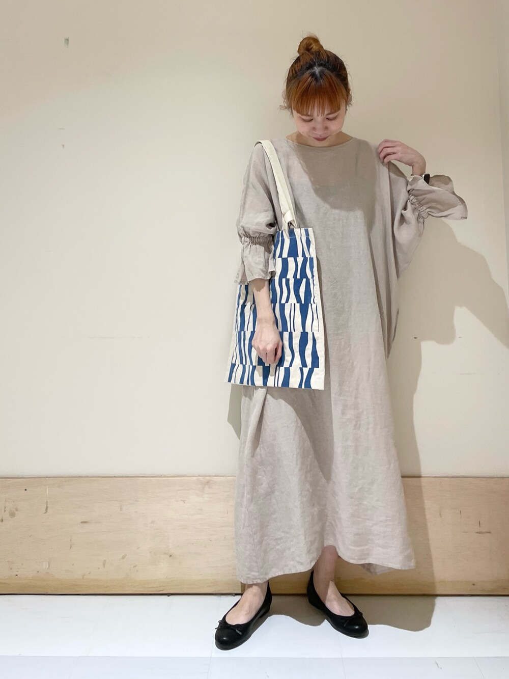 ベージュ系のワンピース、ブルー系のトートバッグ、ブラック系のバレエシューズを着用したレディースの春コーディネートの4枚目の写真