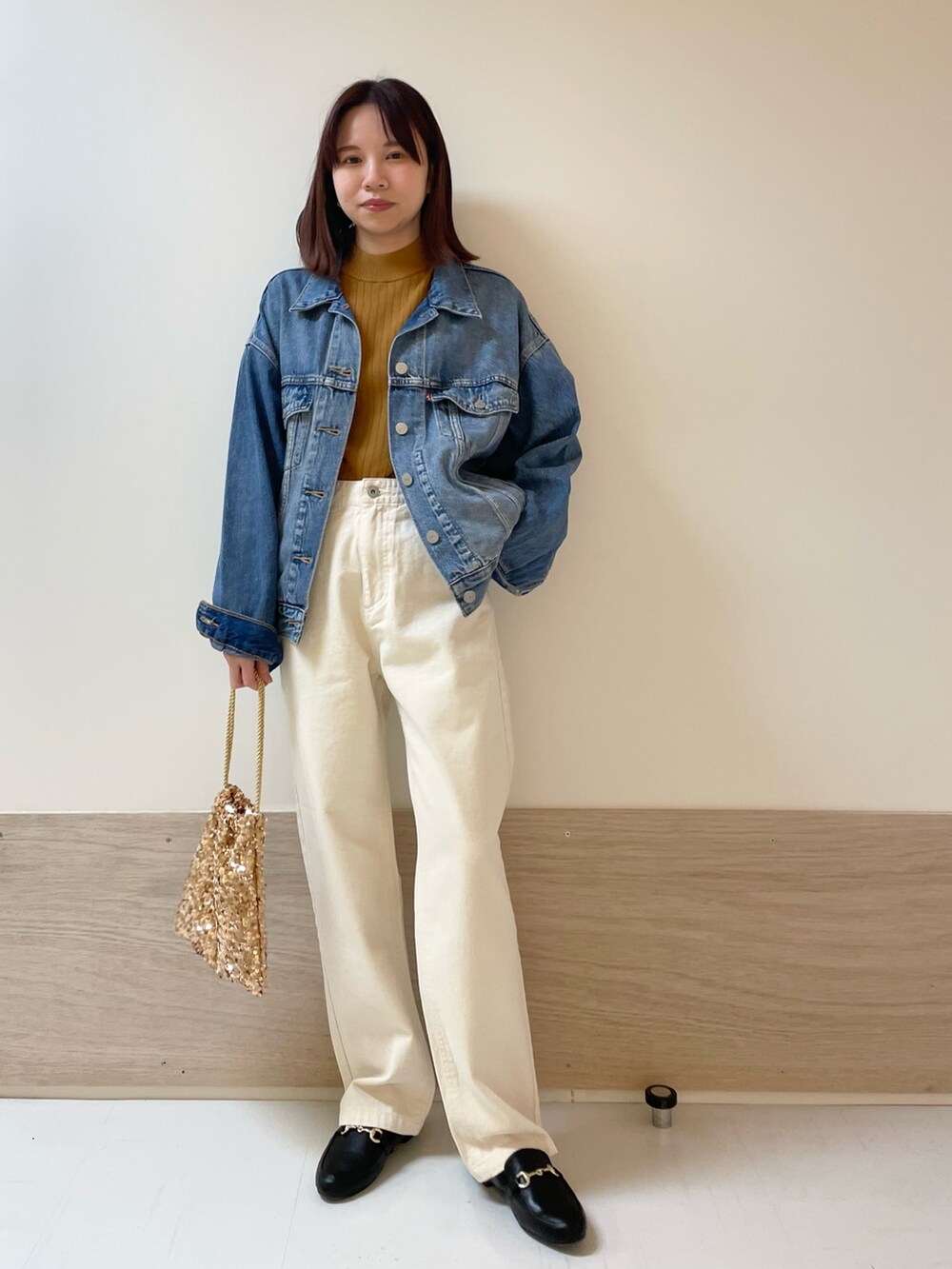 イエロー系のニット/セーター、ベージュ系のデニムパンツ、ブルー系のデニムジャケットを着用したレディースの冬コーディネートの2枚目の写真