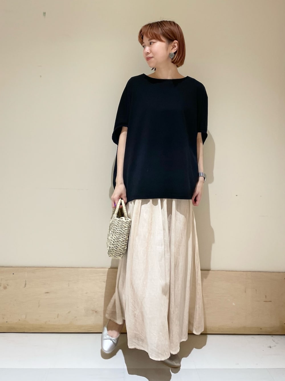 グレー系のかごバッグ、シルバー系のバレエシューズ、ブラック系のTシャツ/カットソーを着用したレディースの春コーディネートの2枚目の写真