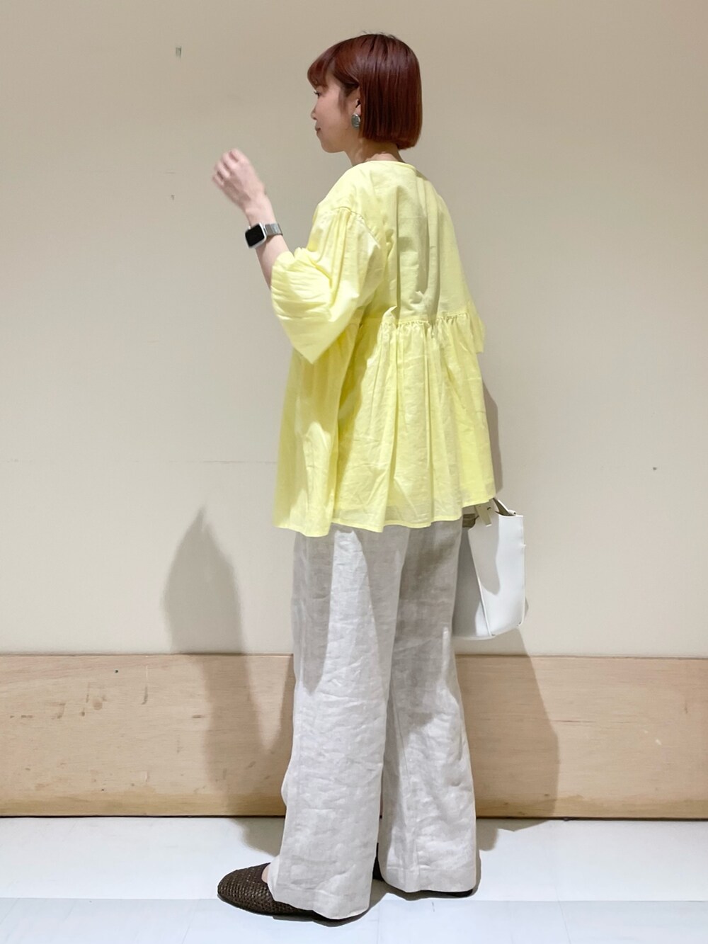 ベージュ系のその他パンツ、イエロー系のシャツ/ブラウス、ホワイト系のトートバッグを着用したレディースの春コーディネートの6枚目の写真