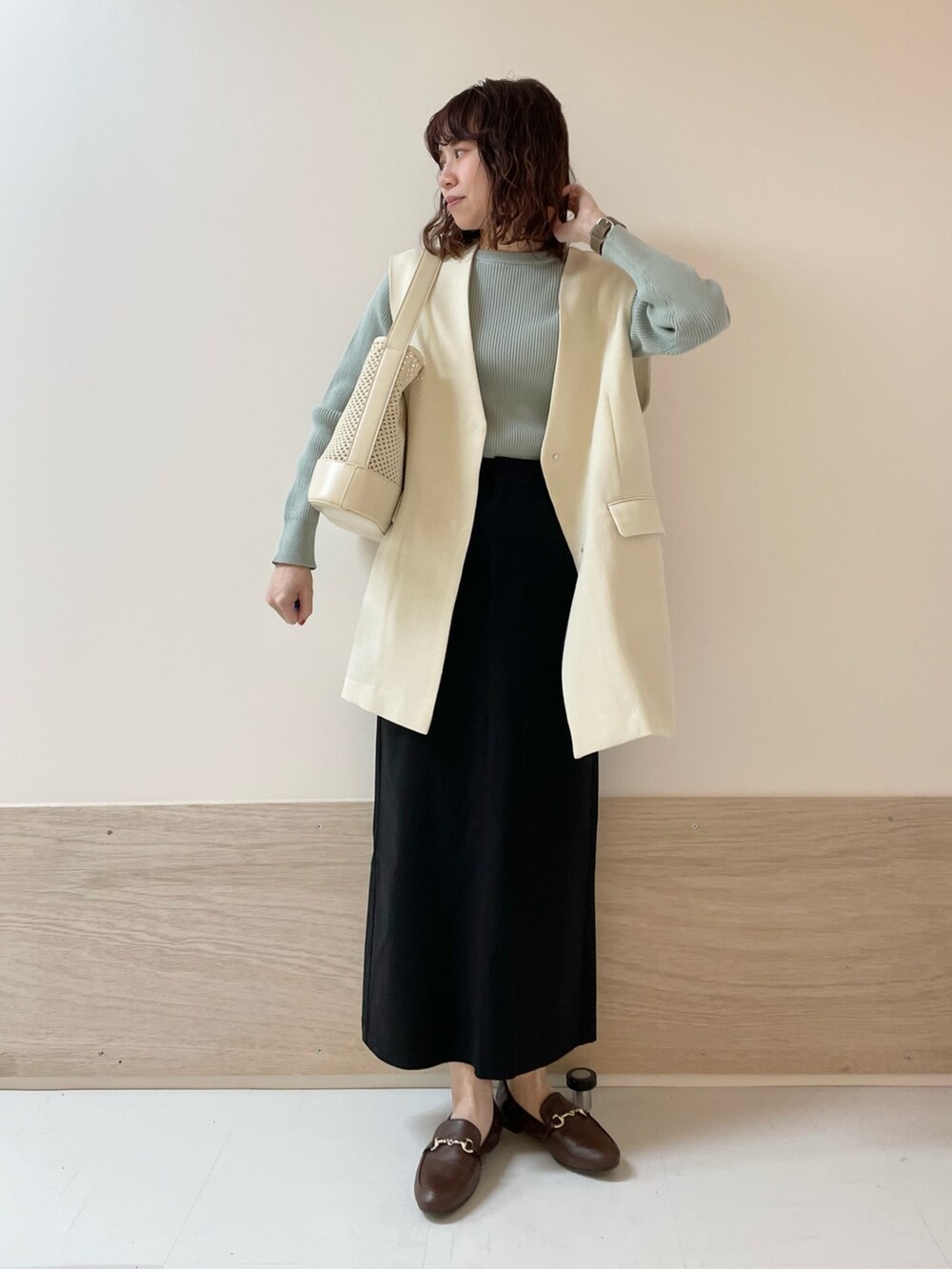 グリーン系のニット/セーター、ホワイト系のその他アウター、ブラック系のスカートを着用したレディースの春コーディネートの3枚目の写真