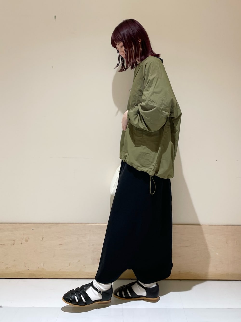 ホワイト系のハンドバッグ、ブラック系のワンピース、グリーン系のその他トップスを着用したレディースの春コーディネートの4枚目の写真