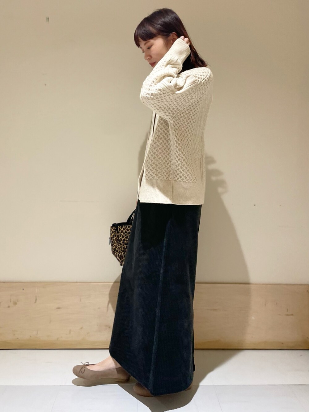 ホワイト系のカーディガン/ボレロ、ブラック系のスカート、ベージュ系のバレエシューズを着用したレディースの冬コーディネートの2枚目の写真