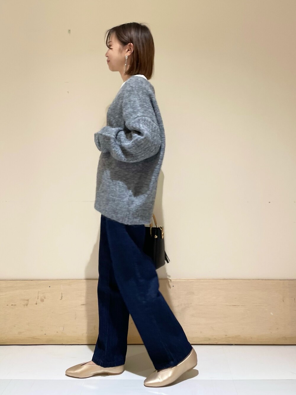 ゴールド系のパンプス、ブラック系のトートバッグ、ブルー系のデニムパンツを着用したレディースの秋コーディネートの3枚目の写真