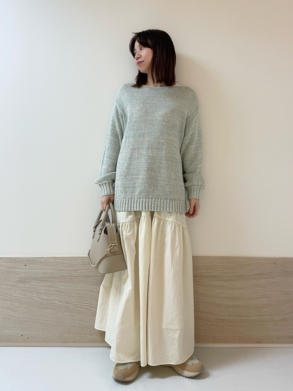 グリーン系のニット/セーター、ホワイト系のスカート、ベージュ系のスニーカーを着用したレディースの春コーディネートの2枚目の写真