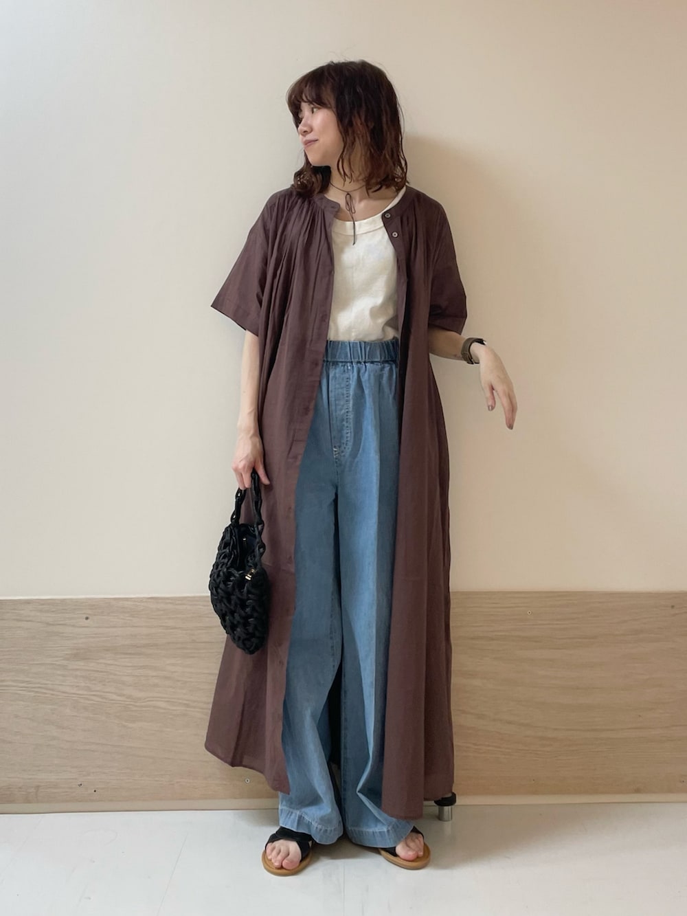 ブルー系のデニムパンツ、ブラック系のサンダル、ブラウン系のワンピースを着用したレディースの春コーディネートの3枚目の写真