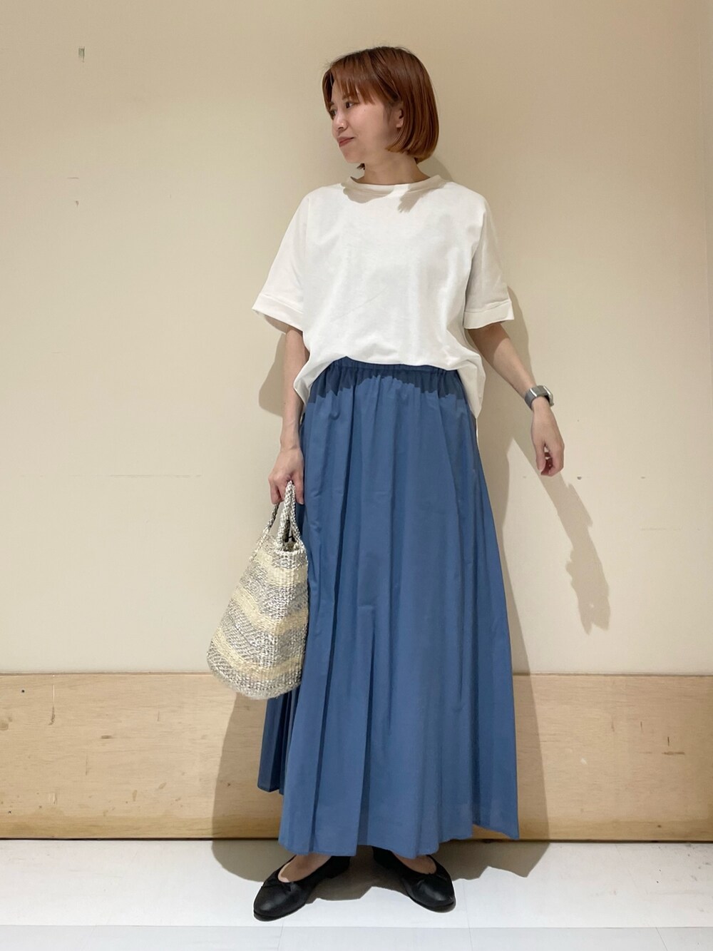 ホワイト系のTシャツ/カットソー、ブルー系のスカート、ホワイト系のハンドバッグを着用したレディースの夏コーディネートの2枚目の写真