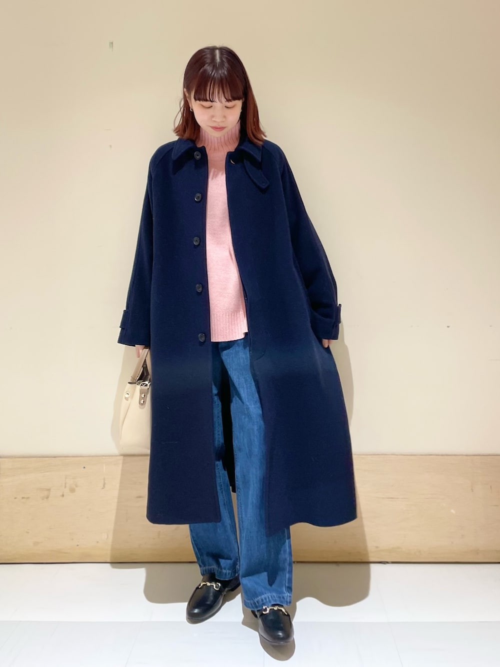 ブルー系のデニムパンツ、ピンク系のニット/セーター、ブルー系のステンカラーコートを着用したレディースの冬コーディネートの3枚目の写真