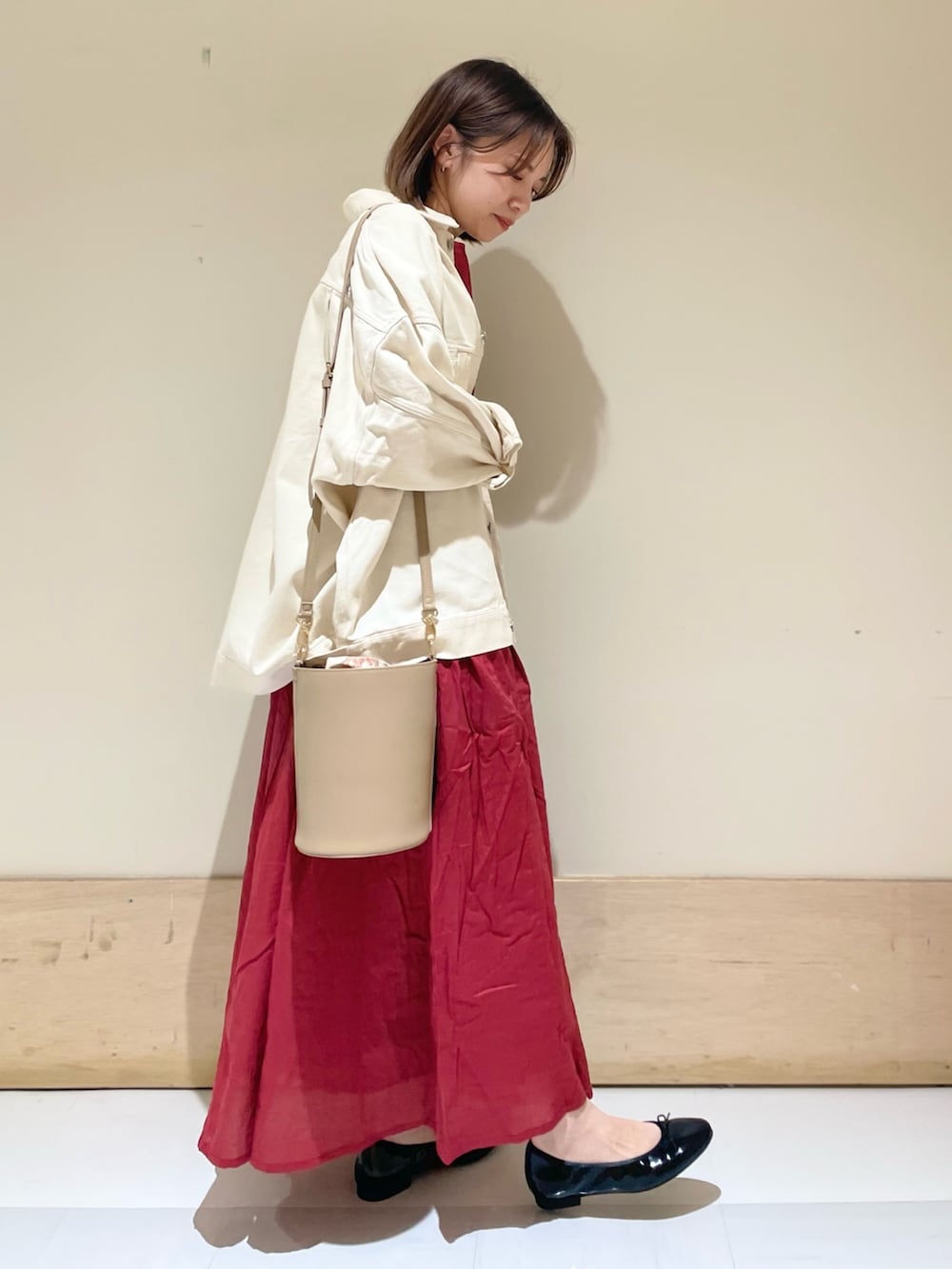 ブラック系のパンプス、ベージュ系のショルダーバッグ、レッド系のワンピースを着用したレディースの秋コーディネートの4枚目の写真