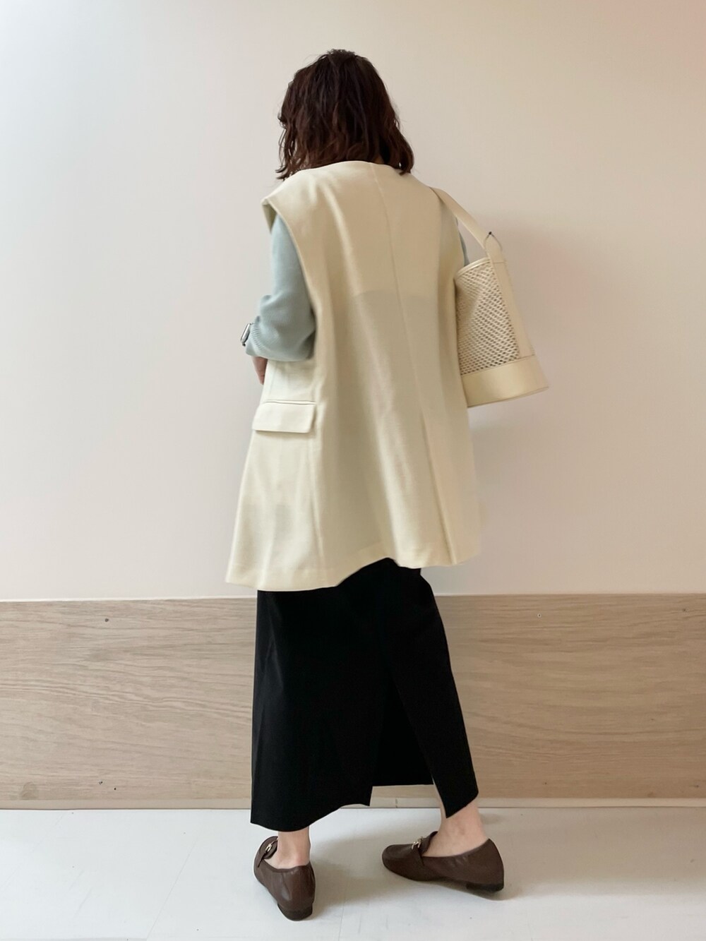 グリーン系のニット/セーター、ホワイト系のその他アウター、ブラック系のスカートを着用したレディースの春コーディネートの5枚目の写真