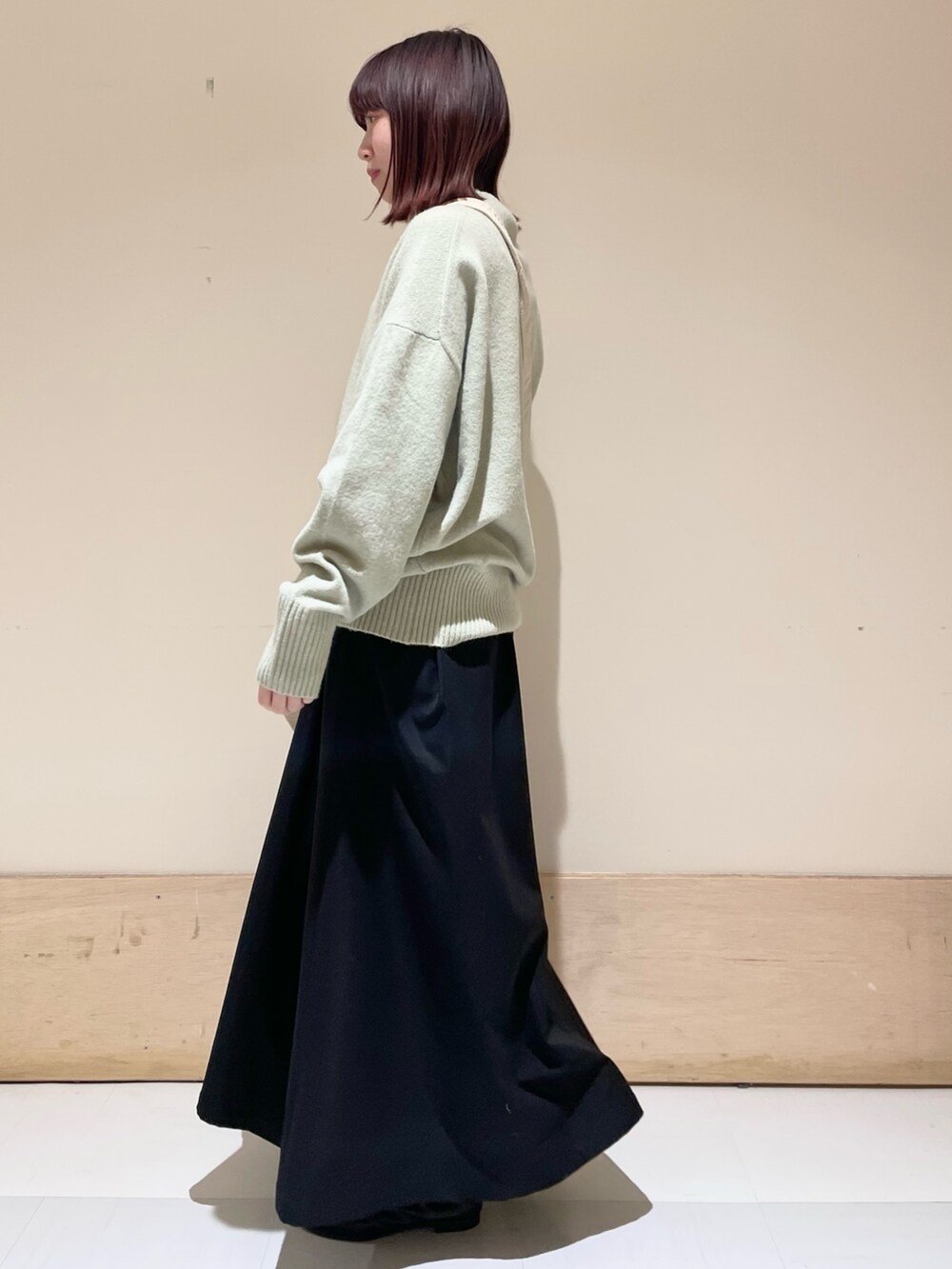 グリーン系のニット/セーター、ブラック系のスカート、グレー系のショルダーバッグを着用したレディースの冬コーディネートの4枚目の写真