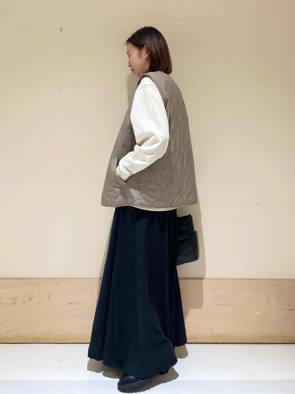 ブラック系のスカート、ブラック系のブーツ、ブラウン系のダウンベストを着用したレディースの秋コーディネートの4枚目の写真