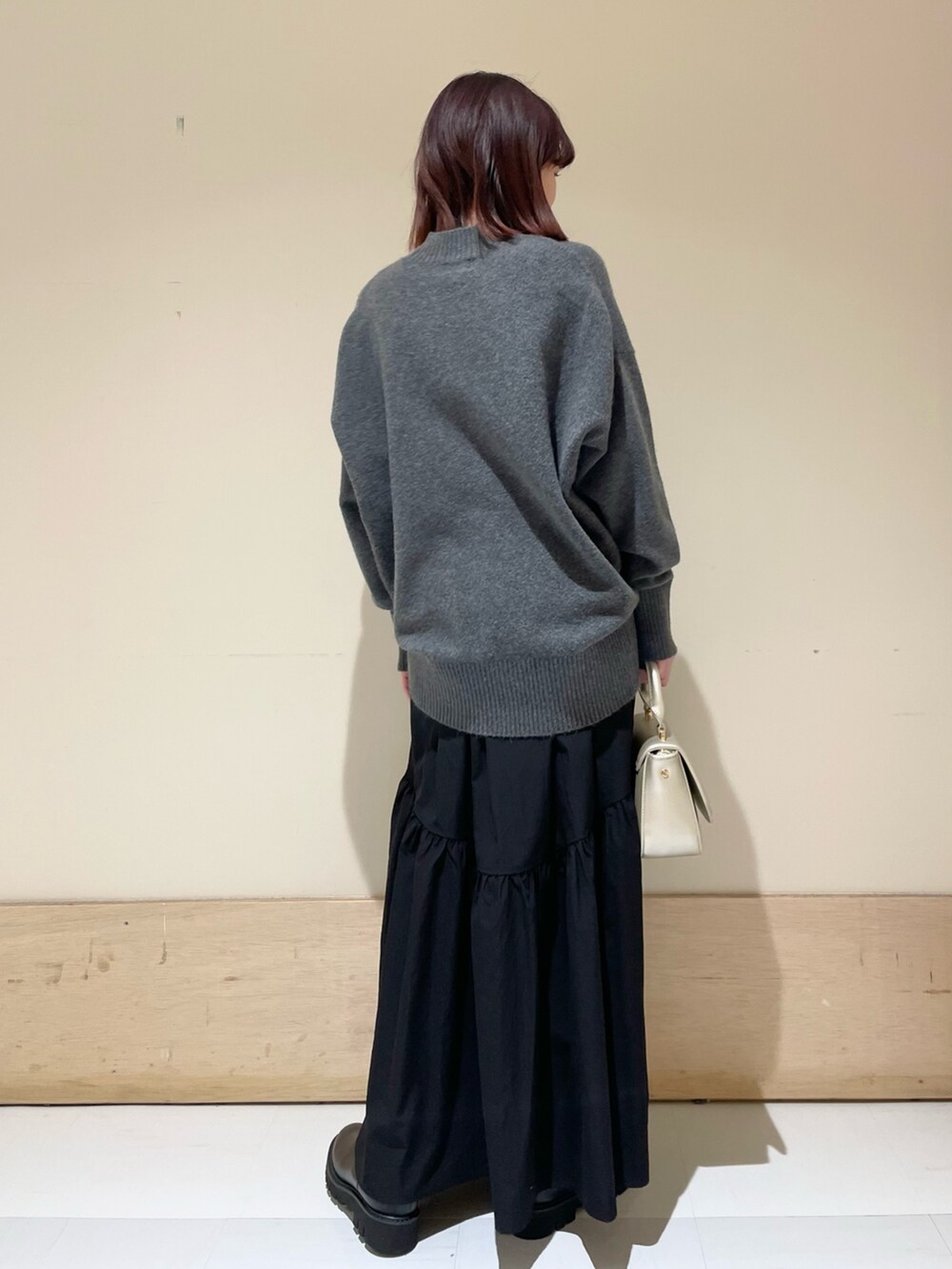 ブラック系のスカート、ゴールド系のショルダーバッグ、ブラック系のブーツを着用したレディースの冬コーディネートの6枚目の写真