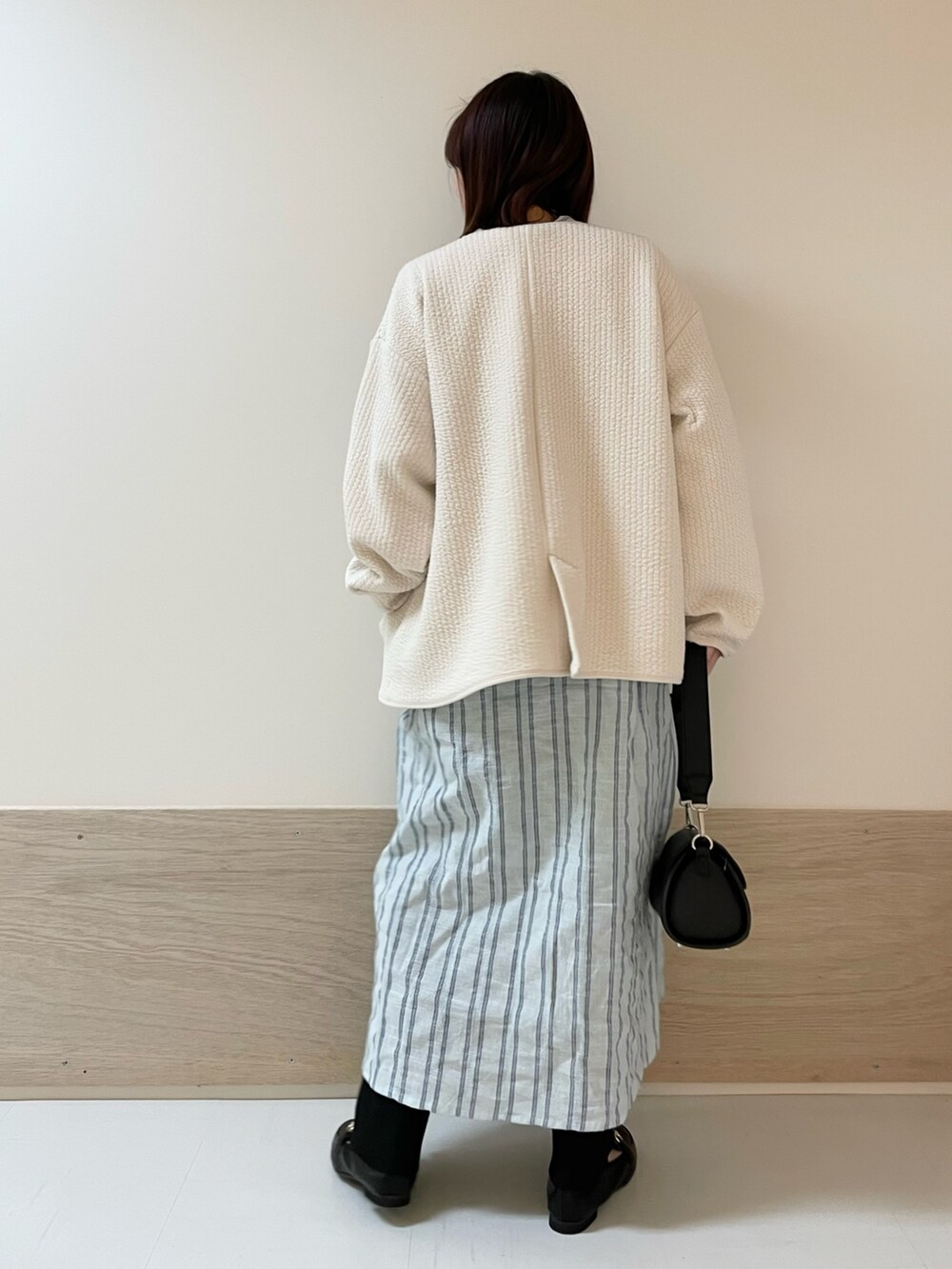 ブラック系のショルダーバッグ、ホワイト系のノーカラージャケット、ブルー系のワンピースを着用したレディースの春コーディネートの6枚目の写真