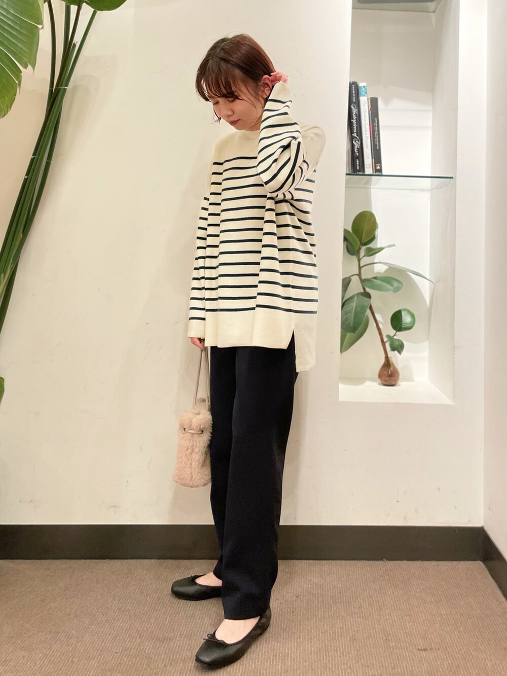 グリーン系のニット/セーター、ブラック系のその他パンツ、ベージュ系のハンドバッグを着用したレディースの冬コーディネートの3枚目の写真