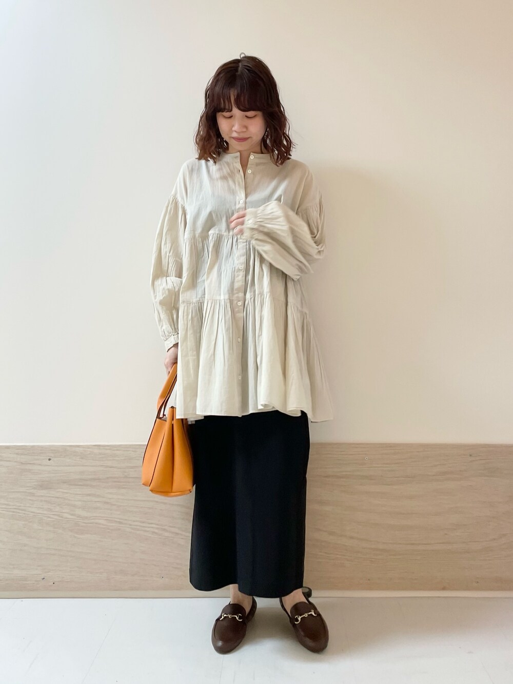 ブラック系のスカート、ホワイト系のチュニックを着用したレディースの春コーディネートの3枚目の写真