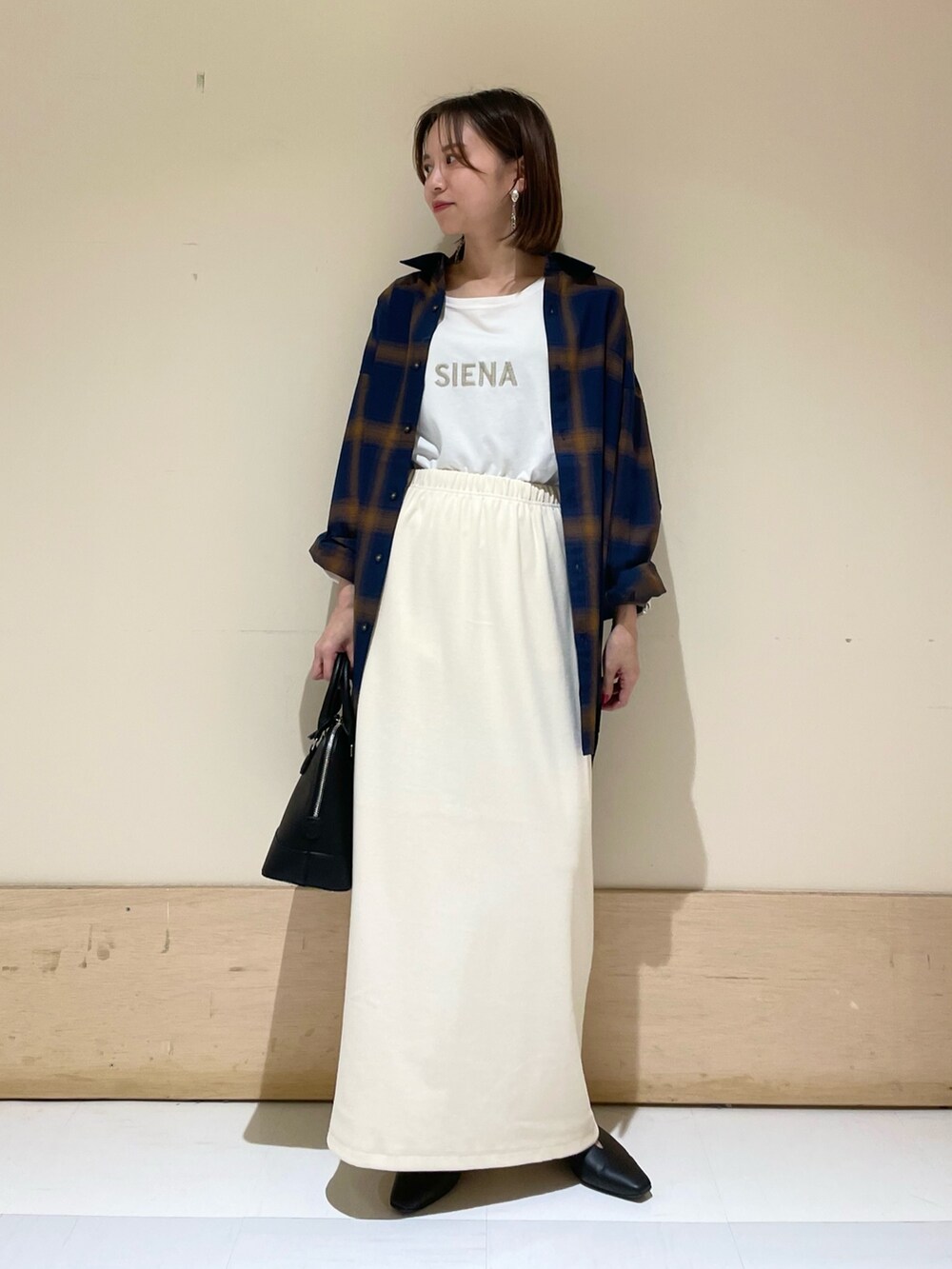 ベージュ系のスカート、ブラック系のパンプス、ブラック系のショルダーバッグを着用したレディースの秋コーディネートの3枚目の写真