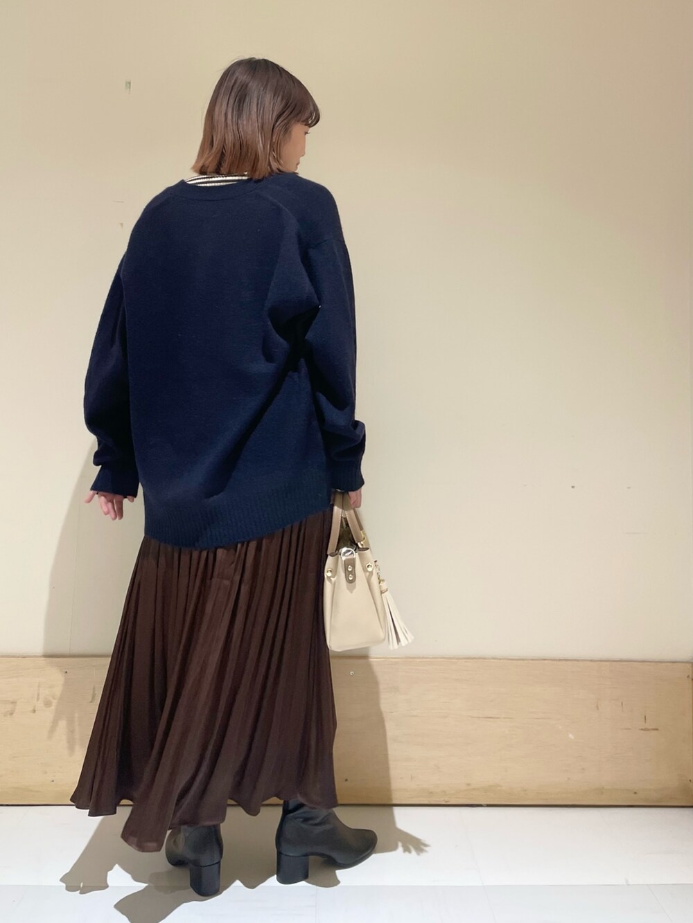 ブルー系のカーディガン/ボレロ、ホワイト系のニット/セーター、ブラウン系のスカートを着用したレディースの冬コーディネートの5枚目の写真