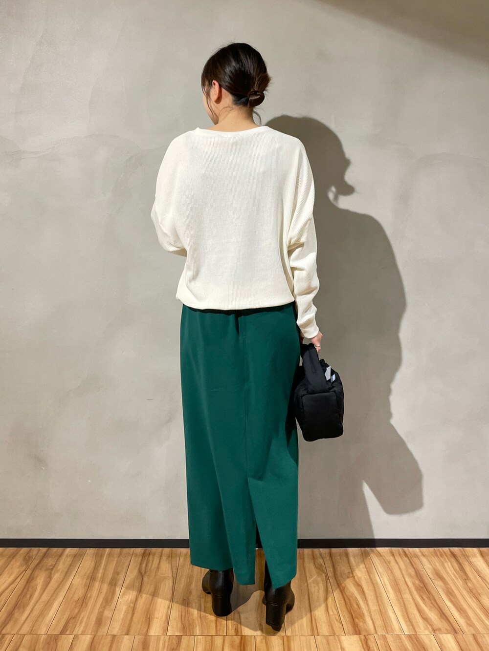 ブラック系のハンドバッグ、ホワイト系のTシャツ/カットソー、グリーン系のスカートを着用したレディースの秋コーディネートの3枚目の写真
