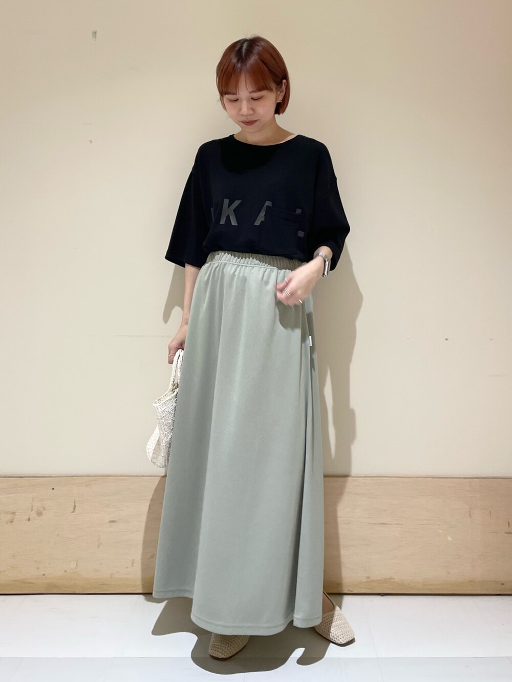グリーン系のスカート、ブラック系のTシャツ/カットソー、ホワイト系のハンドバッグを着用したレディースの春コーディネートの3枚目の写真