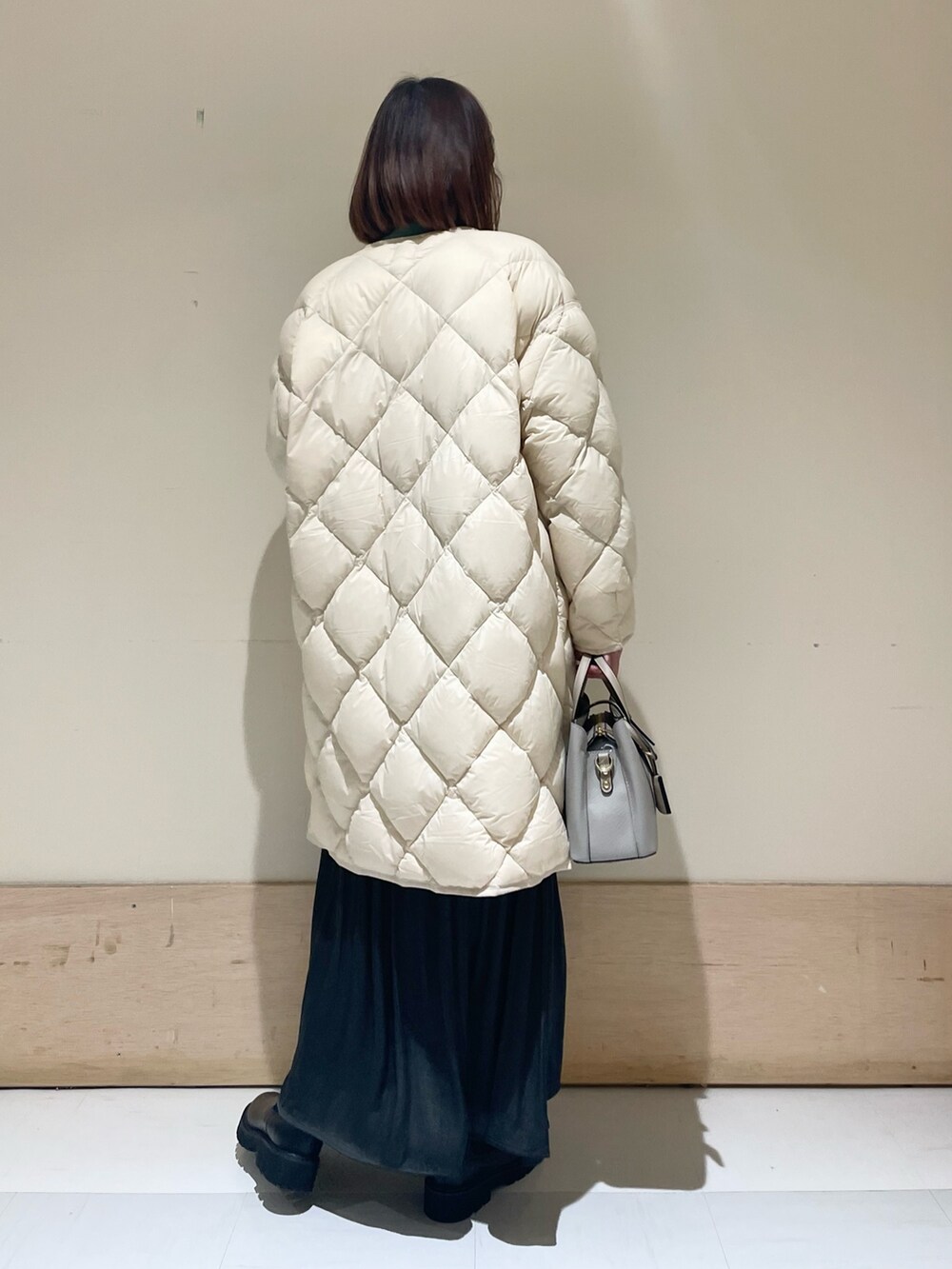 ホワイト系のダウンジャケット/コート、グリーン系のニット/セーター、グレー系のスカートを着用したレディースの冬コーディネートの6枚目の写真