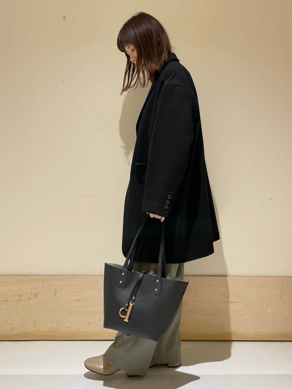 ブルー系のニット/セーター、ブラック系のチェスターコート、グレー系のその他パンツを着用したレディースの冬コーディネートの3枚目の写真