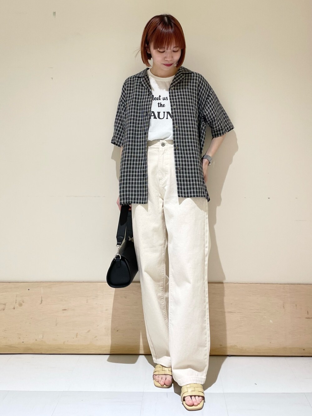 ホワイト系のTシャツ/カットソー、ベージュ系のデニムパンツ、ブラック系のショルダーバッグを着用したレディースの春コーディネートの2枚目の写真