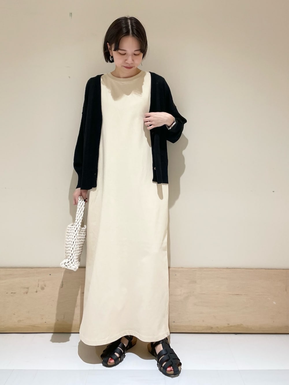 ベージュ系のワンピース、ブラック系のカーディガン/ボレロ、ブラック系のサンダルを着用したレディースの夏コーディネートの2枚目の写真