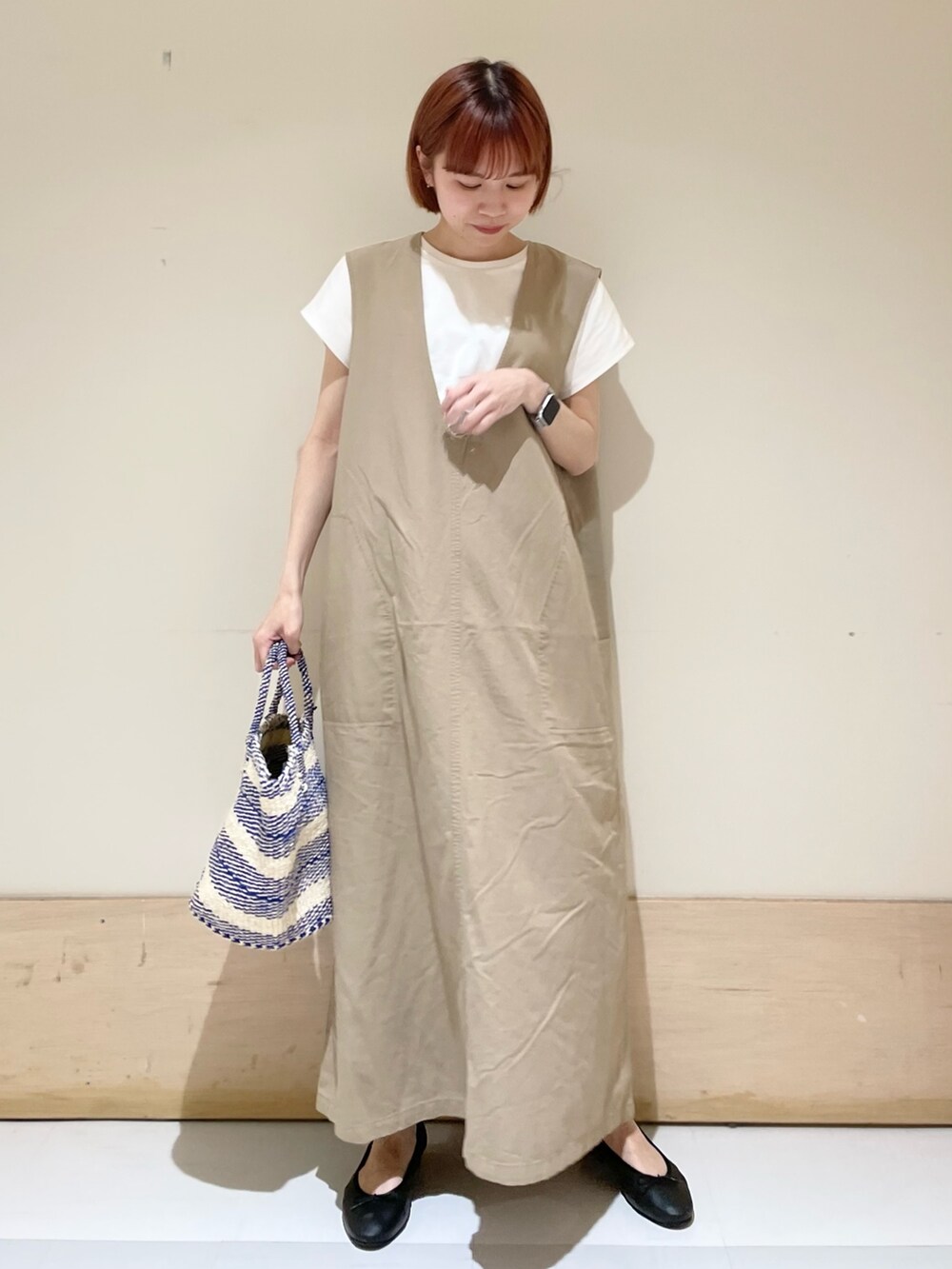 ベージュ系のワンピース、ホワイト系のTシャツ/カットソー、ブラック系のバレエシューズを着用したレディースの春コーディネートの2枚目の写真