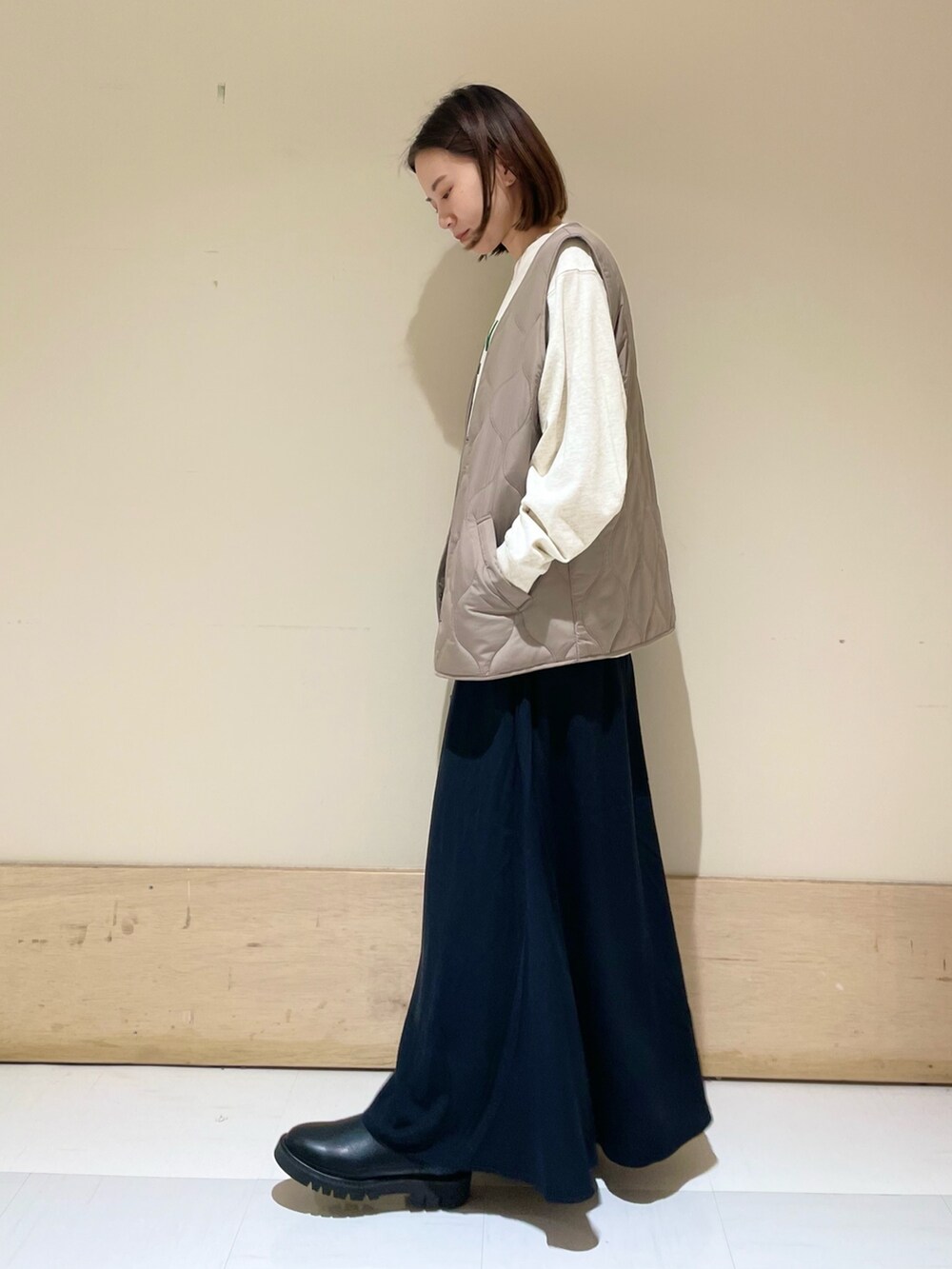 ブラック系のスカート、ブラック系のブーツ、ブラウン系のダウンベストを着用したレディースの秋コーディネートの5枚目の写真