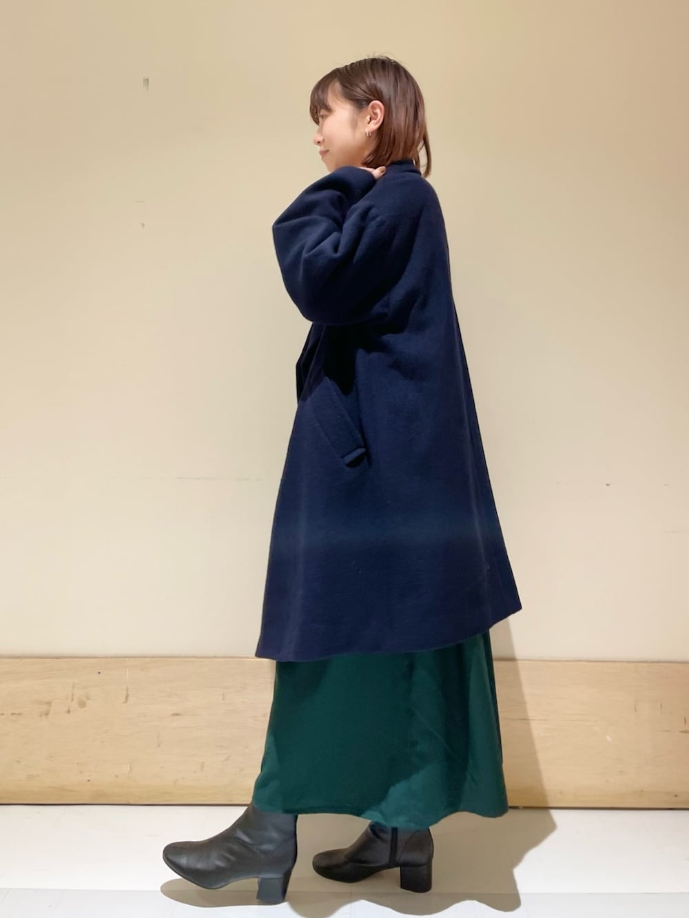 グリーン系のワンピース、ブルー系のピーコート、ブラック系のブーツを着用したレディースの冬コーディネートの4枚目の写真