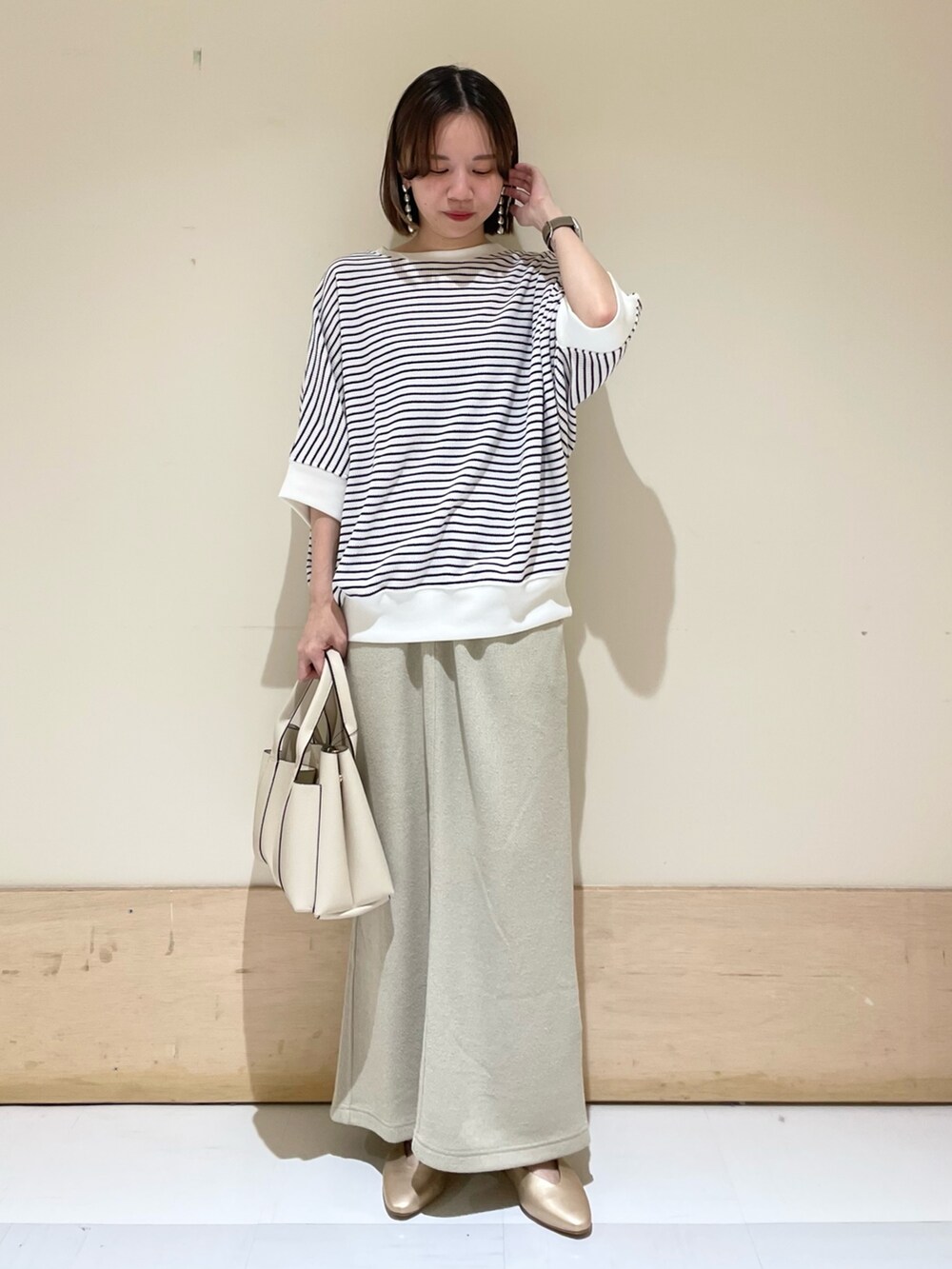 ベージュ系のスカート、ホワイト系のTシャツ/カットソー、ホワイト系のトートバッグを着用したレディースの秋コーディネートの3枚目の写真