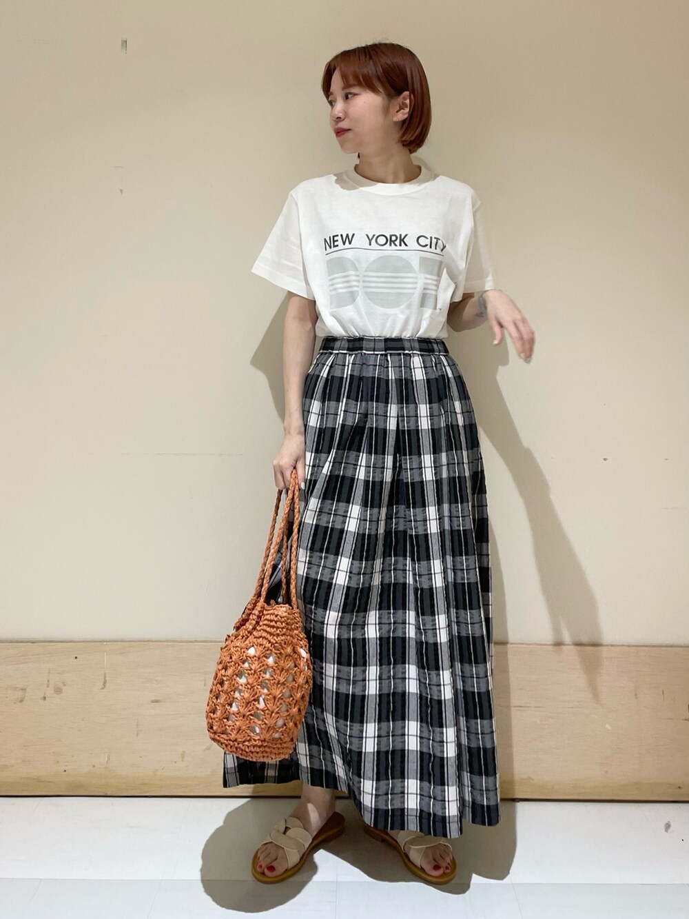 ブラック系のスカート、グレー系のTシャツ/カットソー、ブラウン系のかごバッグを着用したレディースの春コーディネートの2枚目の写真