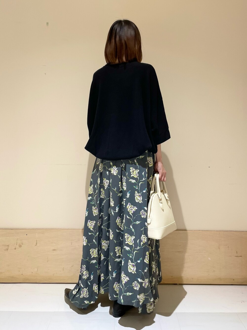 グレー系のスカート、ホワイト系のショルダーバッグ、ブラック系のパンプスを着用したレディースの秋コーディネートの6枚目の写真