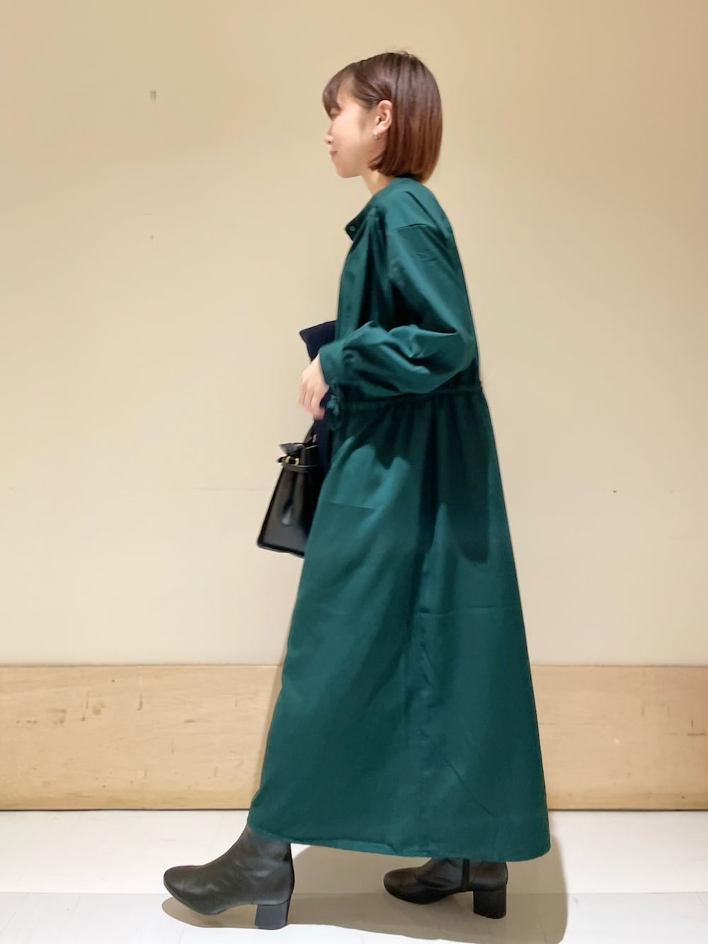 グリーン系のワンピース、ブルー系のピーコート、ブラック系のブーツを着用したレディースの冬コーディネートの9枚目の写真