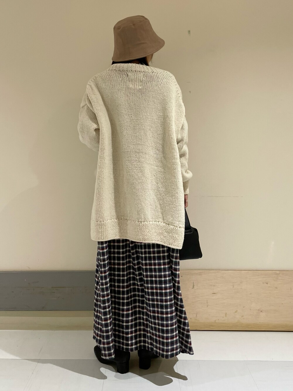 ブラウン系のワンピース、ホワイト系のカーディガン/ボレロ、ブラック系のブーツを着用したレディースの秋コーディネートの3枚目の写真