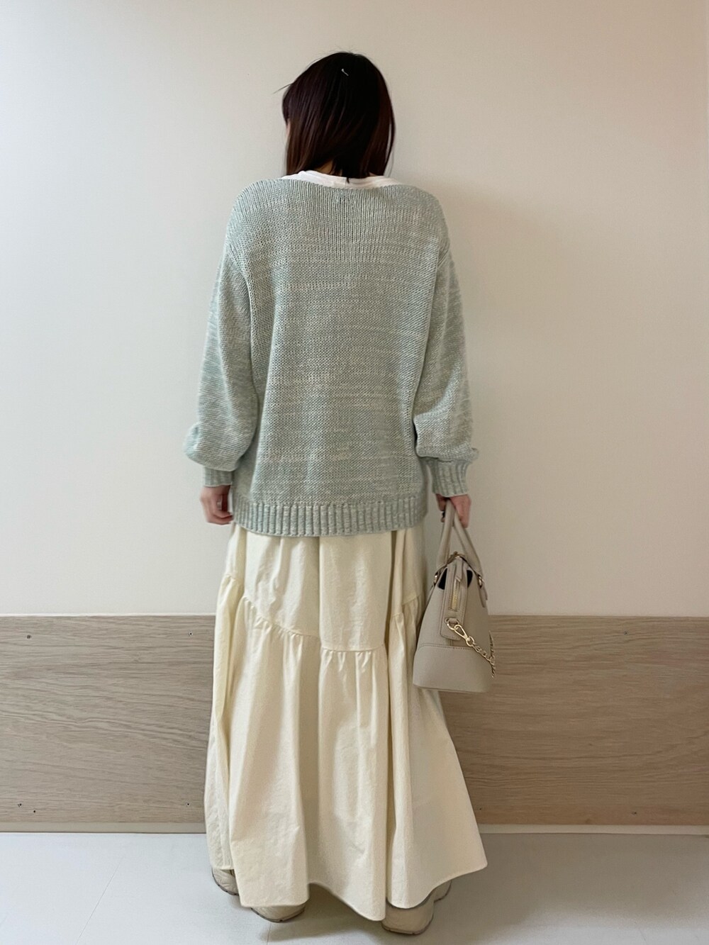 グリーン系のニット/セーター、ホワイト系のスカート、ベージュ系のスニーカーを着用したレディースの春コーディネートの6枚目の写真