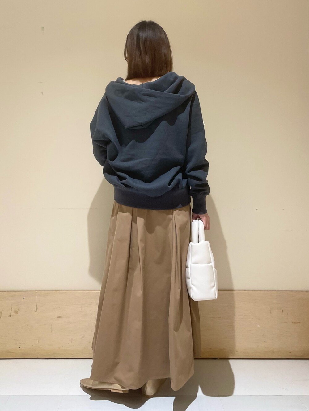 ゴールド系のパンプス、ホワイト系のトートバッグ、ベージュ系のスカートを着用したレディースの秋コーディネートの7枚目の写真